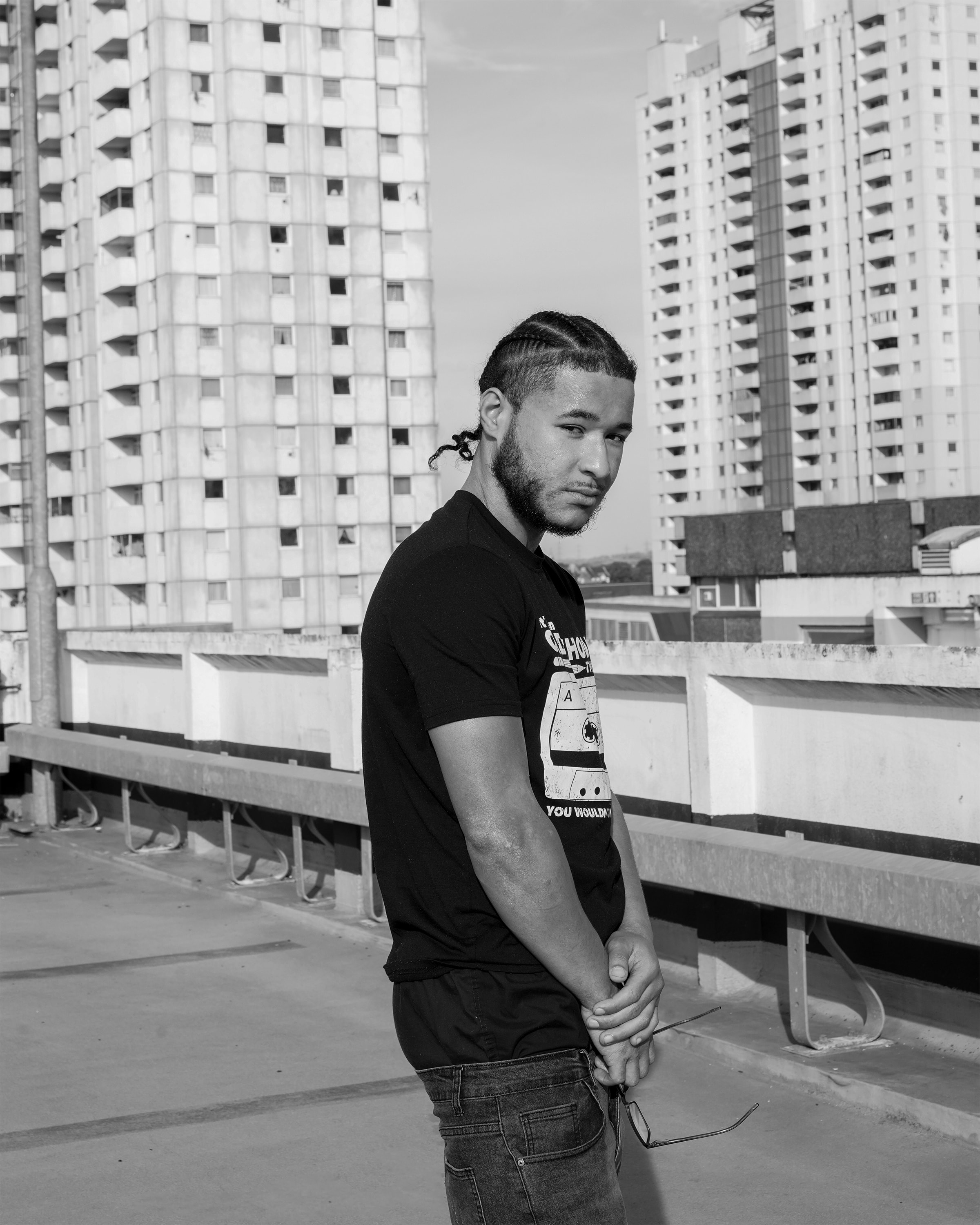 Squintz posing on a rooftop with urban apartment buildings